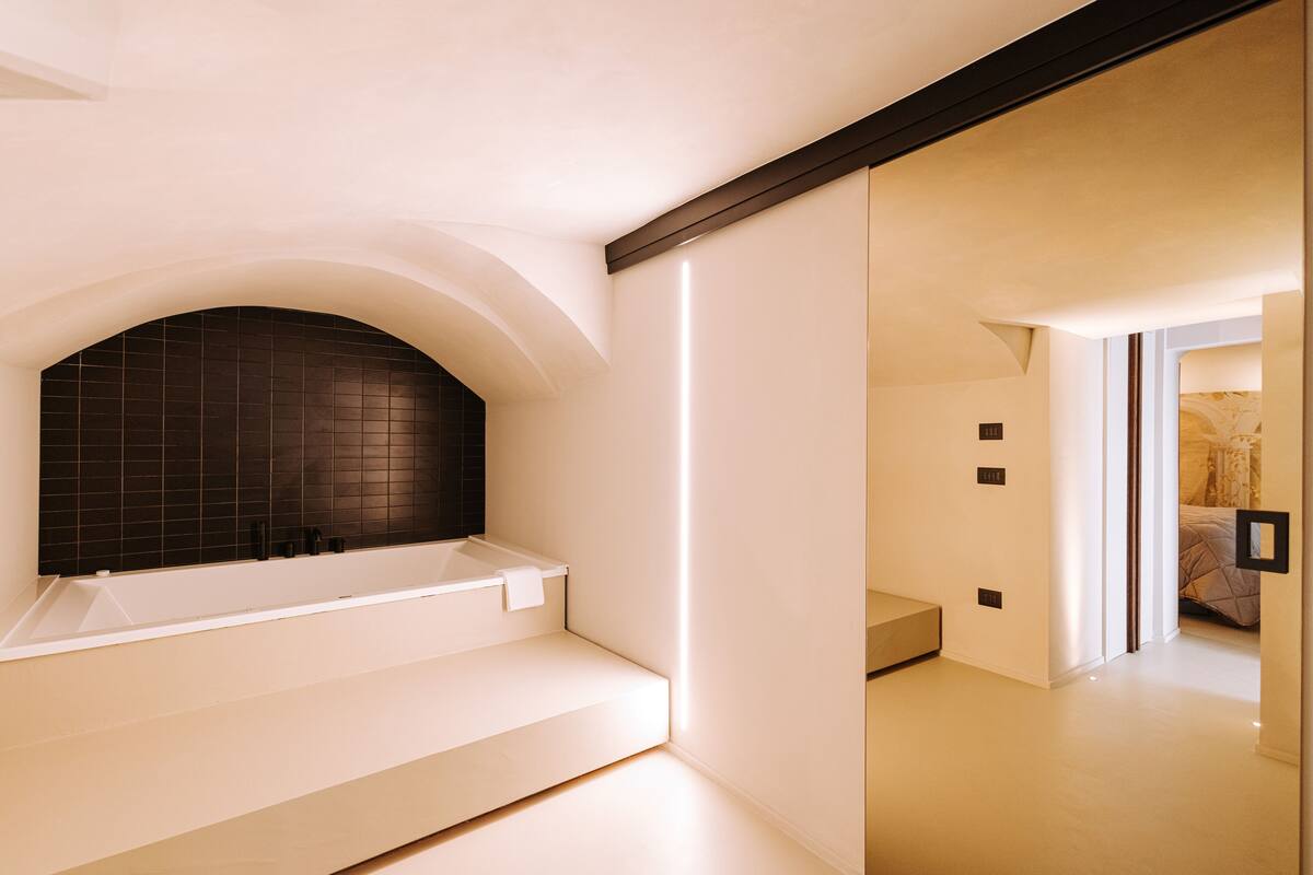A modern bathroom with a freestanding bathtub, a tiled wall, and a minimalist design.
