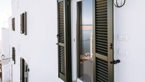 En hvid bygning med et skilt med nummer 53, en dør med skodder og en lille balkon.