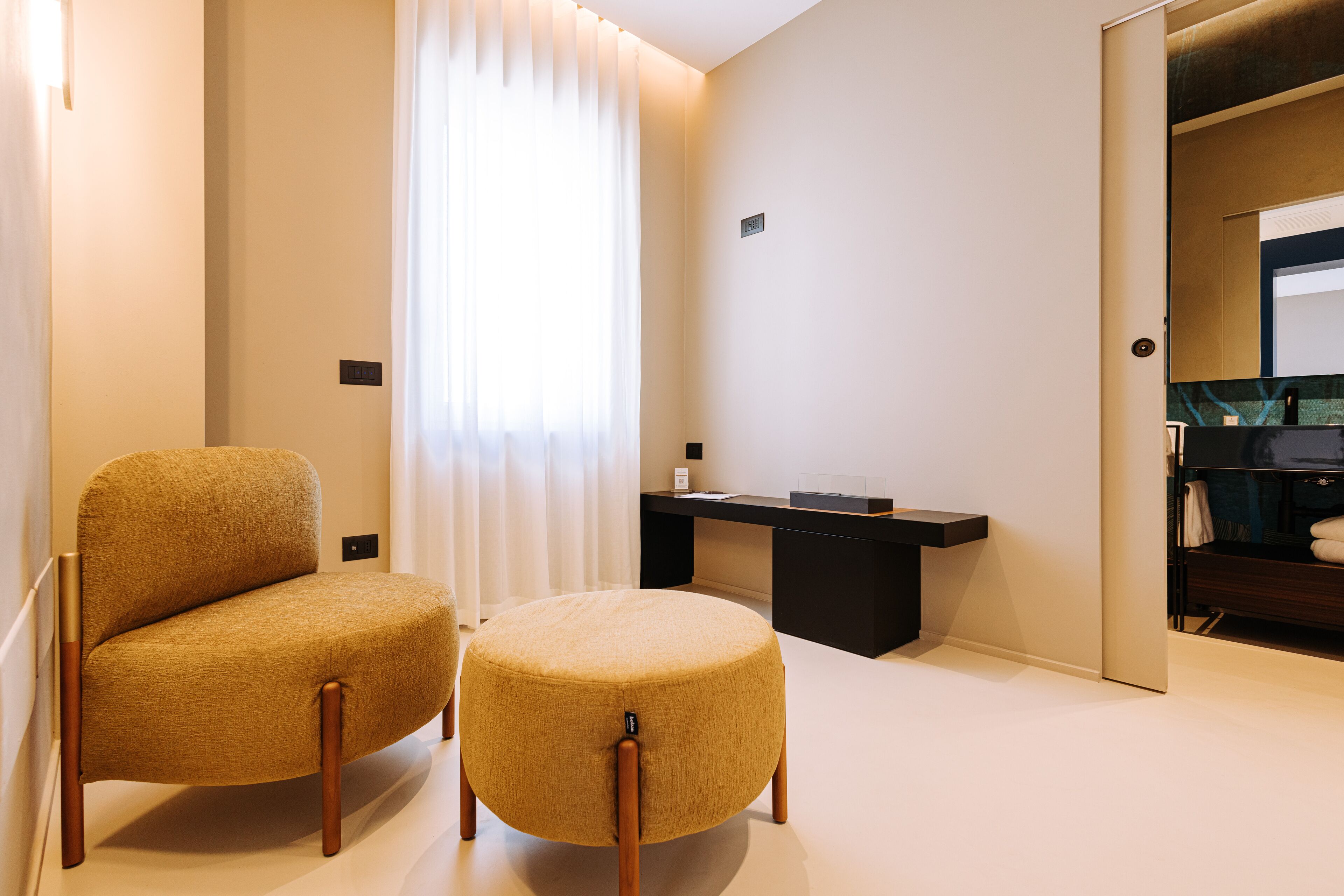 Habitación de hotel con sofá, reposapiés y un escritorio pequeño con espejo.