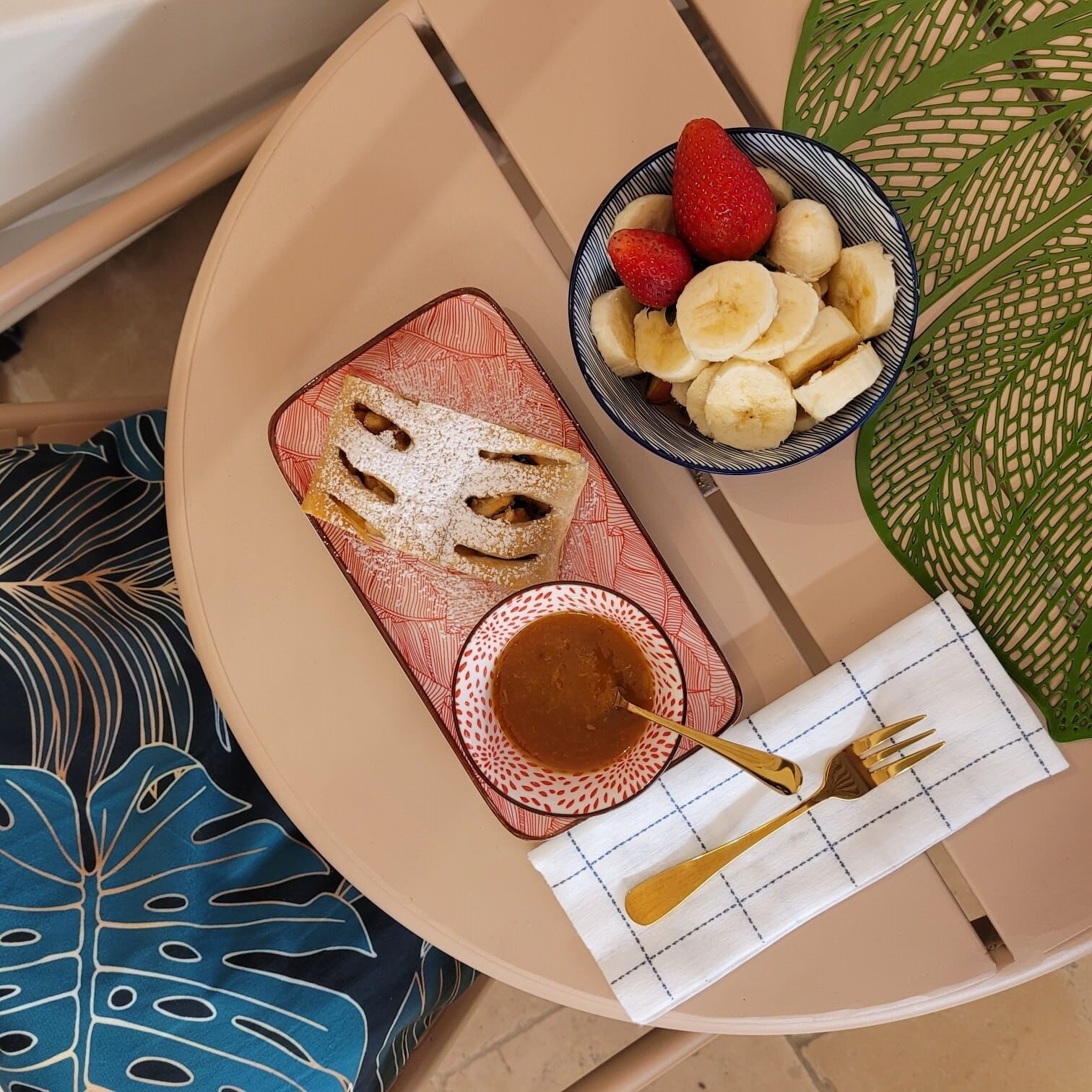 A table with a plate of pancakes, a bowl of fruit, and a cup of coffee.