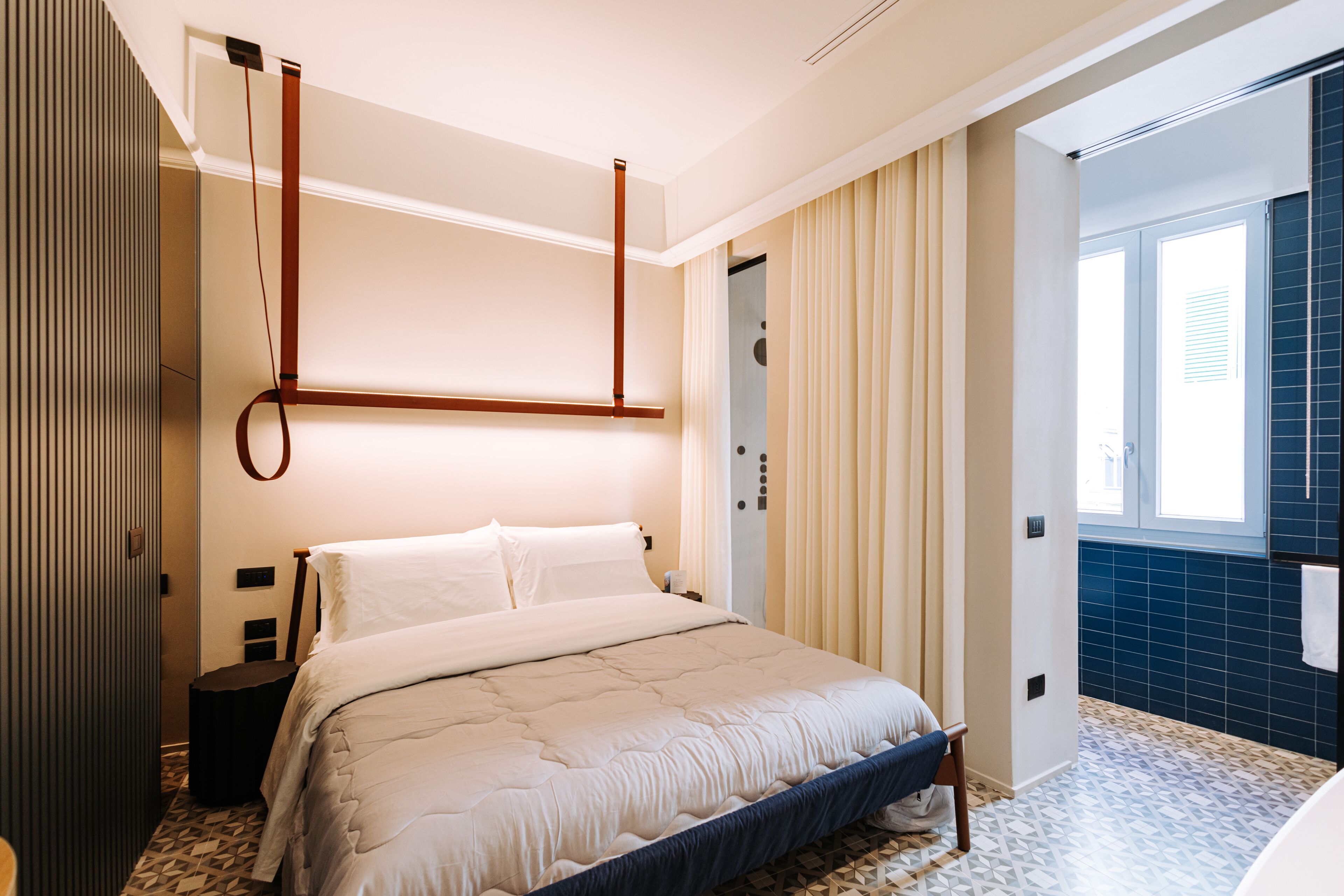 Un dormitorio moderno con cama, mesitas de noche, una ventana con cortinas y una puerta.