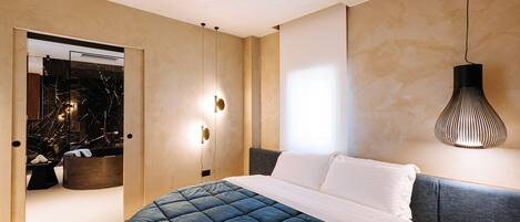 A modern bedroom with a large bed, a bedside table, a mirror, and a hanging light fixture.