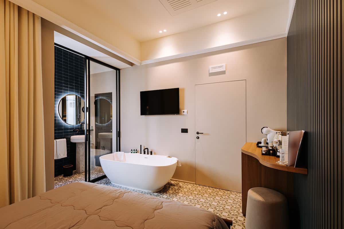 A modern bathroom with a freestanding bathtub, a large mirror, and a mounted TV.
