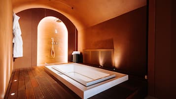 Une salle de spa moderne dotée d’une grande baignoire, d’un plancher en bois et d’un porte-serviettes.
