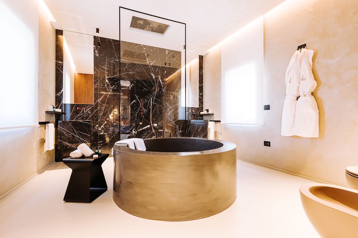 A modern bathroom with a large freestanding bathtub, a glass-enclosed shower, and a marble backsplash.