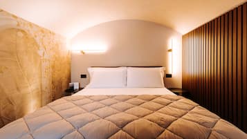 A neatly made bed with a quilted headboard, a bedside table with a lamp, and a wall with vertical wooden slats.