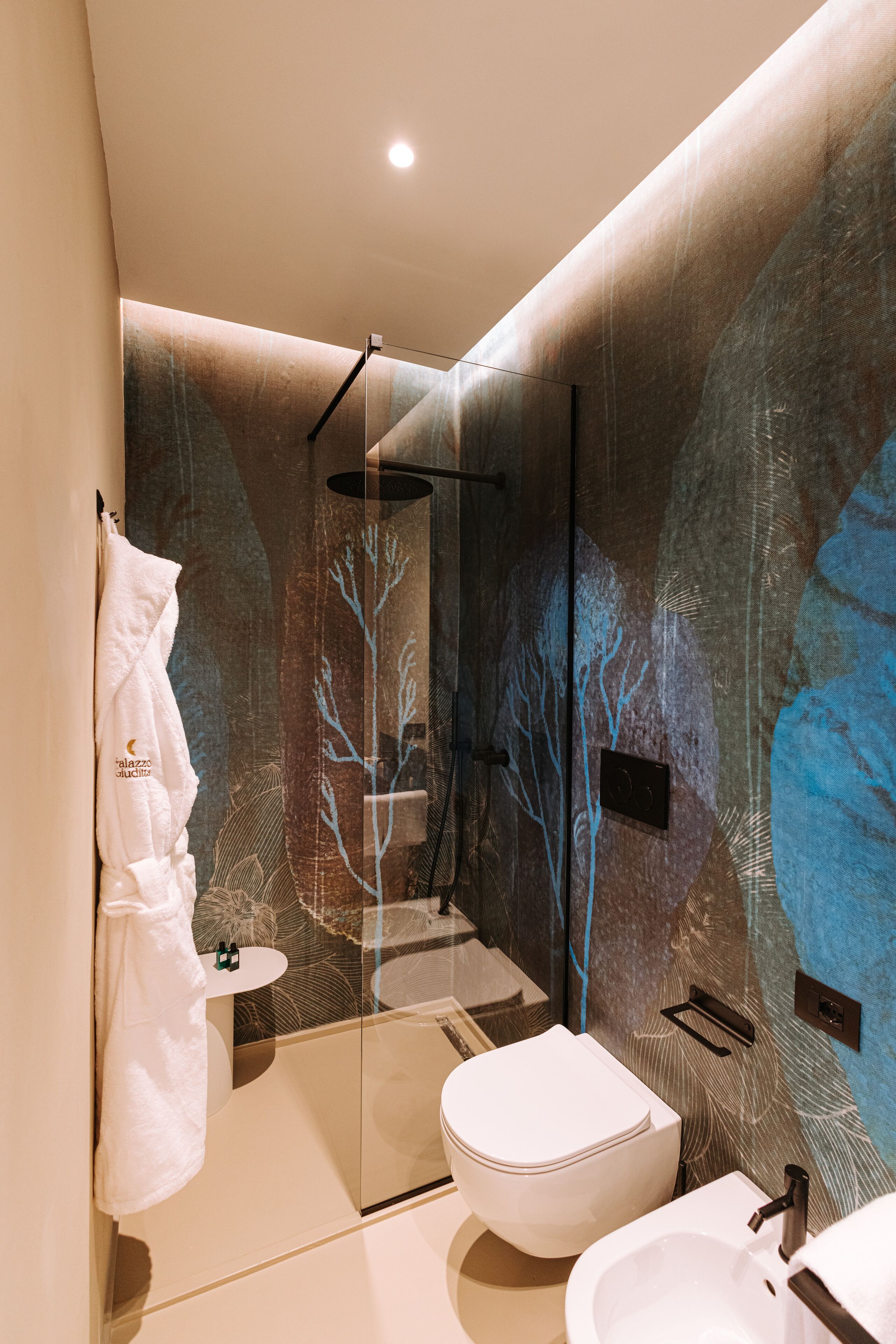 A modern bathroom with a glass-enclosed shower, a white toilet, and a sink.