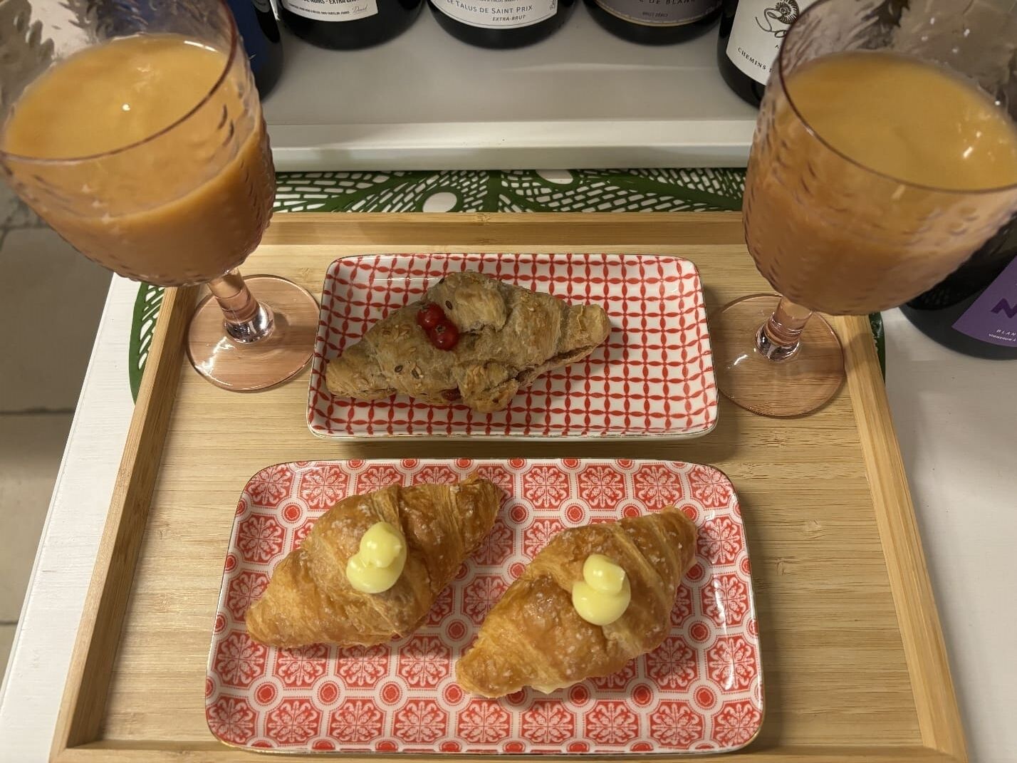 A tray with two pastries and two glasses of a beverage, likely coffee or tea, on a table with a patterned tablecloth.