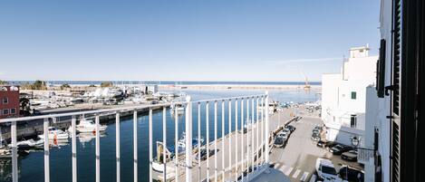 A marina with boats docked, a clear sky, and a view of the sea.