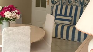A room with a round table, a chair, a sofa with striped cushions, and a patterned wall.