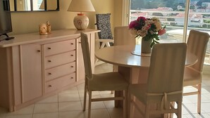 A dining area with a round table, chairs, a lamp, and a vase of flowers.