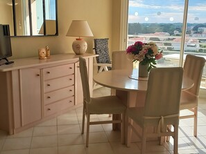 Un coin repas avec une table ronde, des chaises, une lampe et un vase de fleurs.