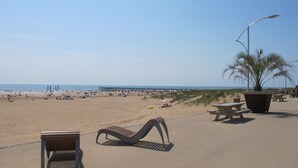 A beach with a wooden bench, a picnic table, and a street lamp.