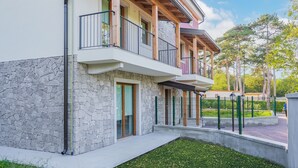 A modern two-story building with balconies, stone facade, and a fenced courtyard. - Residence Mare Azzurro (Duino-Aurisina)