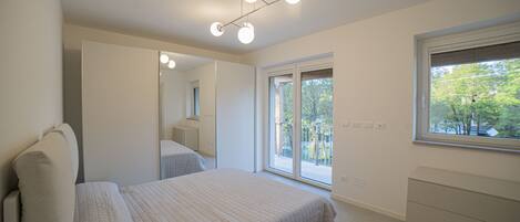 A bedroom with a bed, a dresser, a window, and a mirror.
