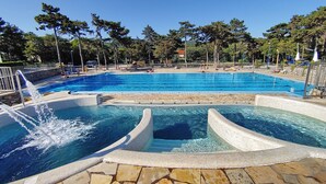 A swimming pool with a water feature, surrounded by stone tiles and trees. - Residence Mare Azzurro (Duino-Aurisina)