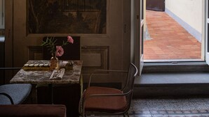 A dining area with a table set for two, a mural on the wall, and a view of the street outside. - Stella d'Italia (Florence)