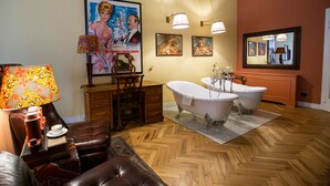 A bathroom with a wooden herringbone floor, a clawfoot bathtub, a white sink, and a wooden vanity. - Stella d'Italia (Florence)