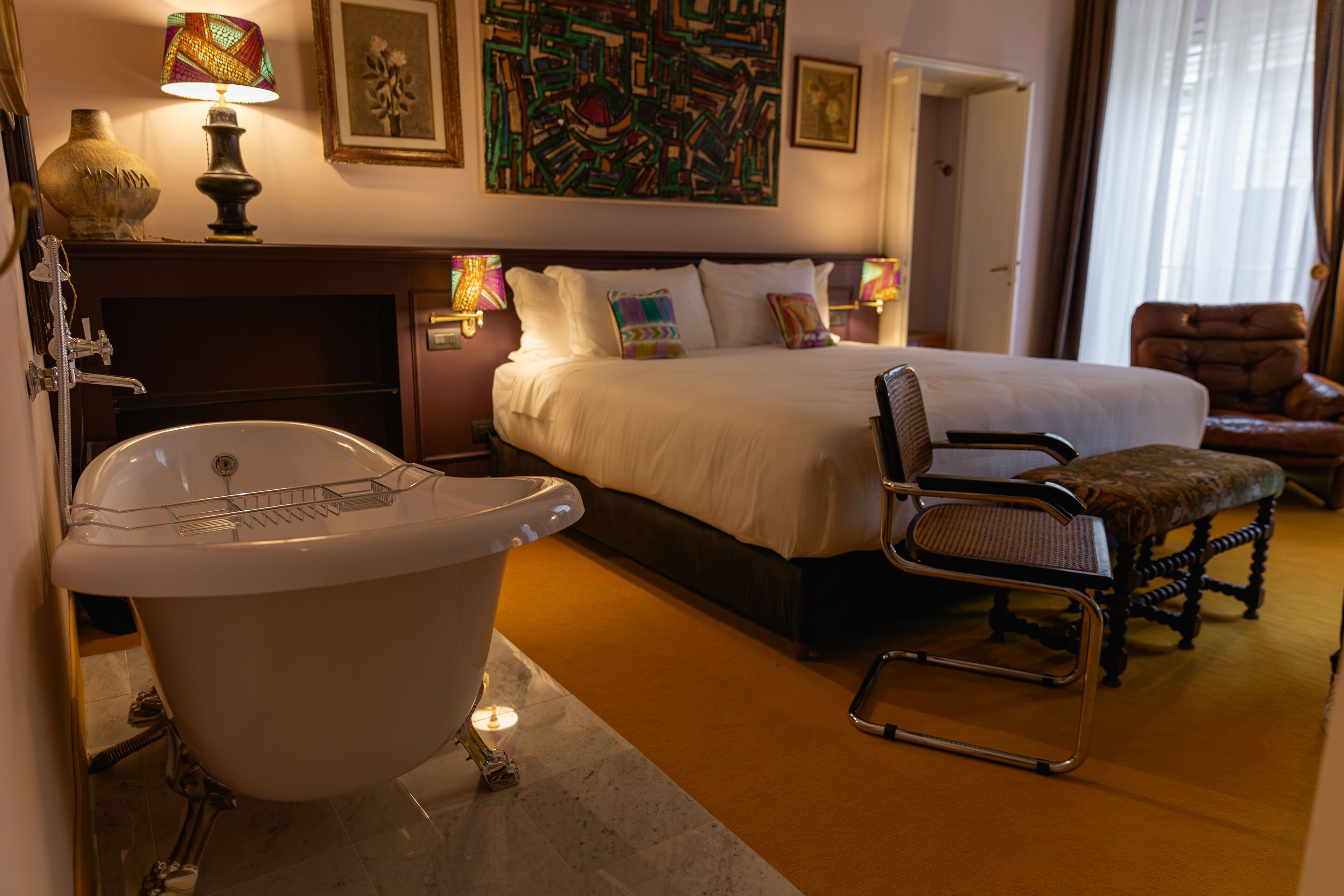 Une chambre d’hôtel avec un grand lit, une baignoire, une chaise et un bureau.