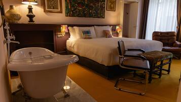 Une chambre d’hôtel avec un grand lit, une baignoire, une chaise et un bureau.