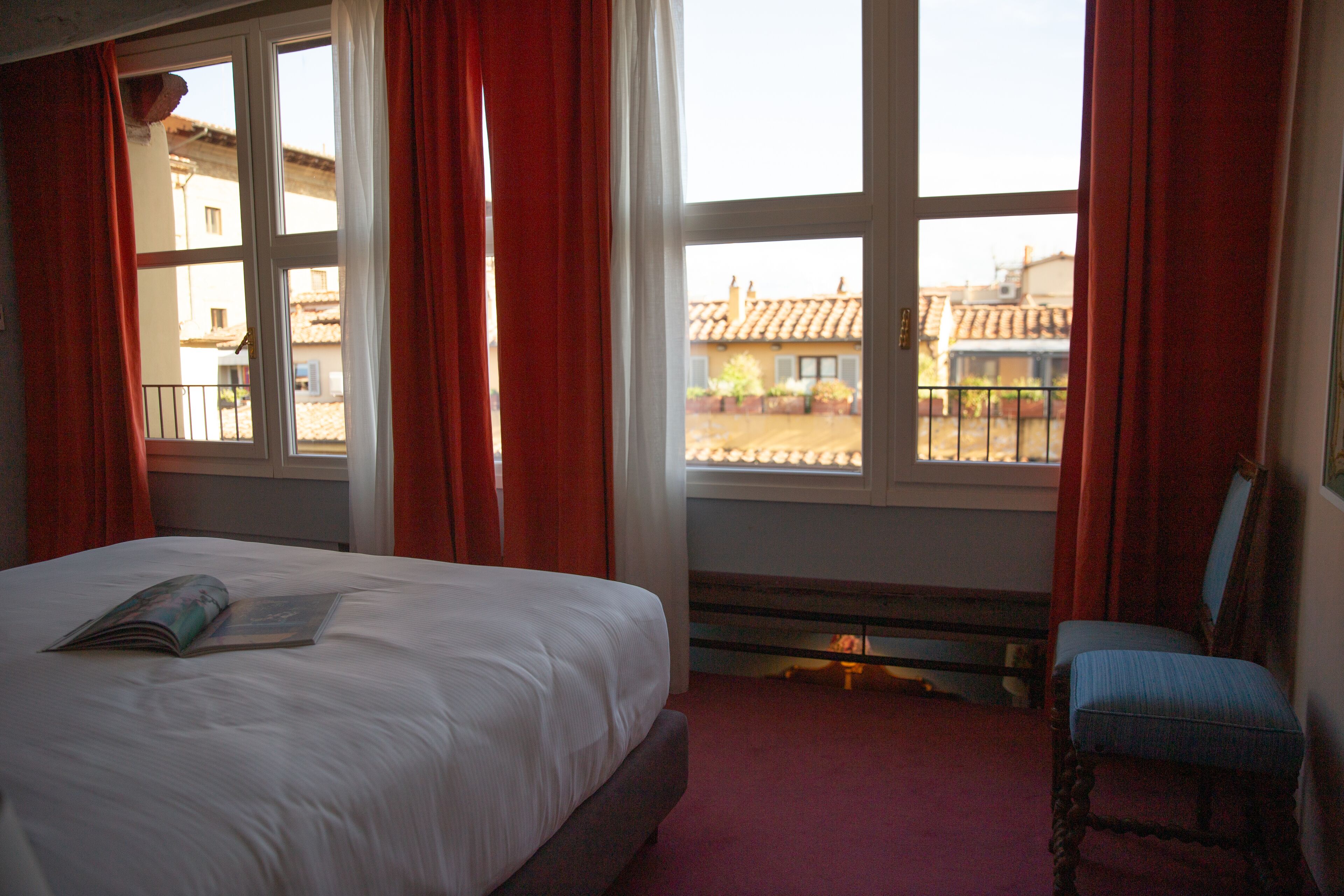 Une chambre à coucher avec un lit, une chaise et une fenêtre avec des rideaux.