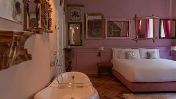 A bedroom with a large bed, a white bathtub, and multiple mirrors on the walls.