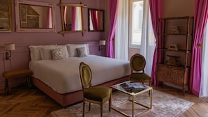 A bedroom with a large bed, two chairs, a small table, and a shelf with decorative items. - Stella d'Italia (Florence)