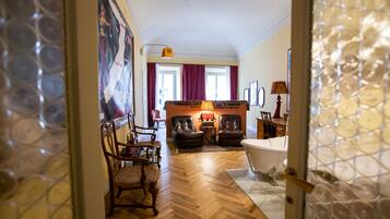 A living room with a fireplace, leather chairs, a sofa, and a large painting on the wall.