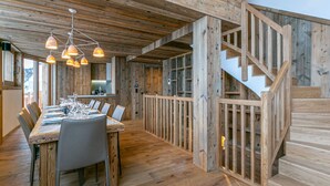 A rustic wooden interior with a dining area, staircase, and wooden walls.