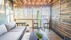 Una terraza de madera con un sofá, sillas y una mesita con una planta.