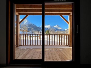 Eine Holztür mit Blick auf verschneite Berge und eine Holzdiele.
