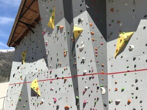 A rock climbing wall with various holds and a red safety line.