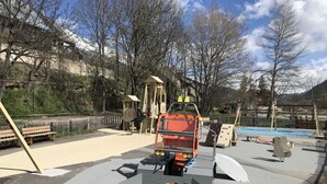 Un parque infantil con estructuras para escalar, un tobogán y un arenero.