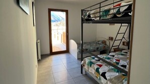 Habitación tipo dormitorio con literas, una puerta que da a un espacio exterior y un radiador en la pared.