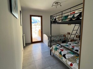 A dorm-style room with bunk beds, a door leading to an outdoor area, and a radiator on the wall.