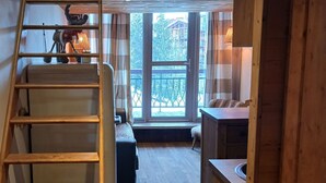 A wooden interior with a staircase, a sofa, a small table, and a window with a view of buildings. - Cozy duplex for 5 with balcony and WIFI in Arc 1800 (Les Arcs 1800)