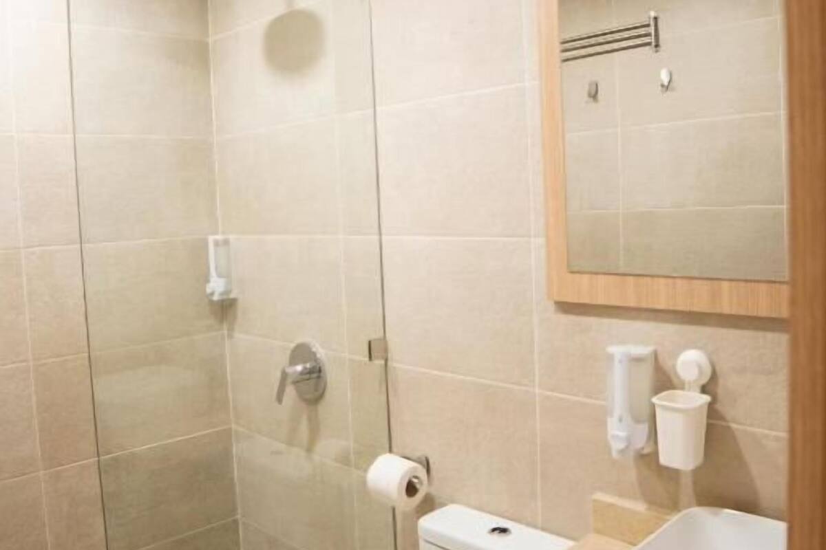 Un baño moderno con cabina de ducha de vidrio, inodoro y lavabo con espejo.