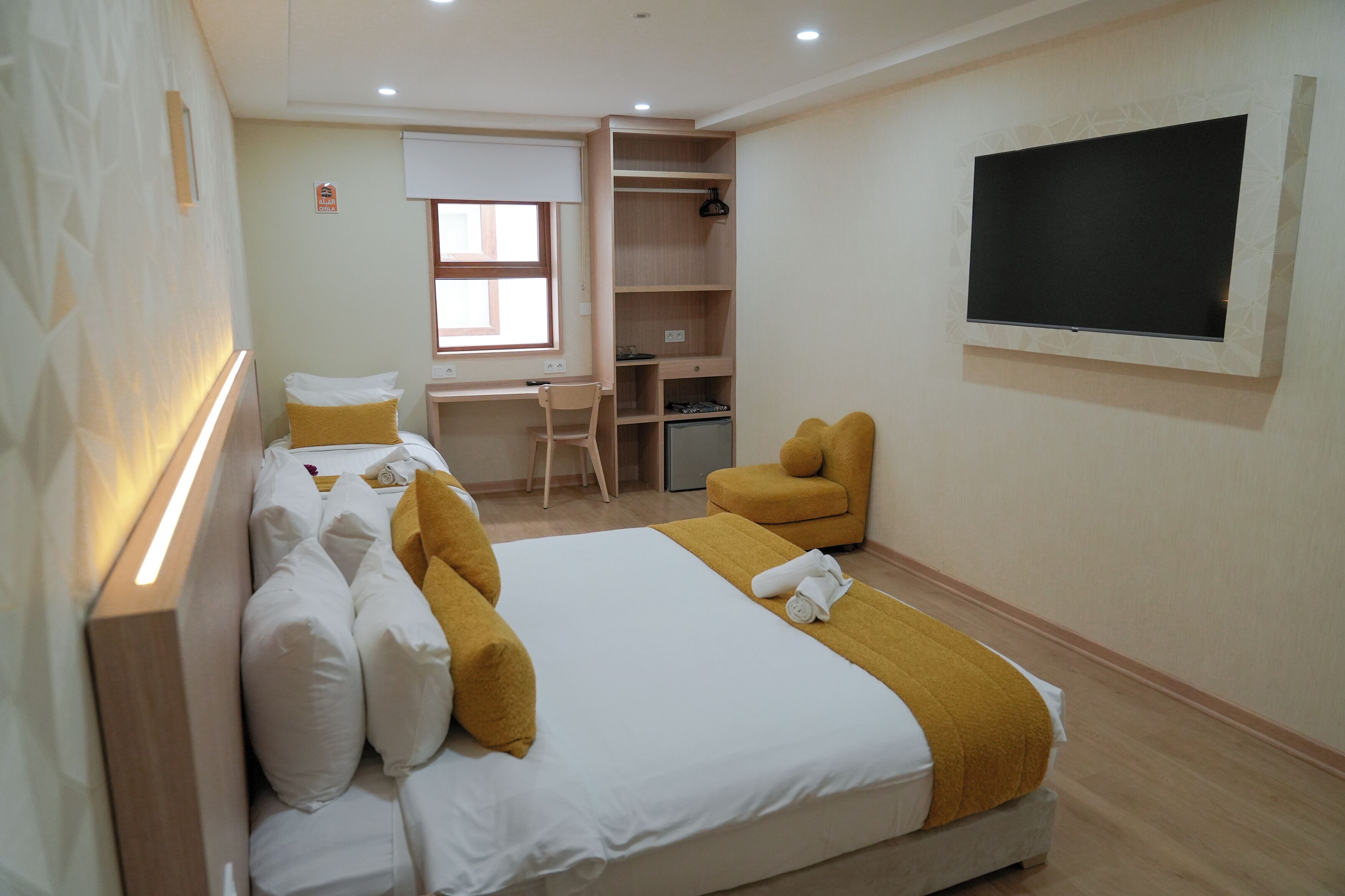 Ein Hotelzimmer mit einem großen Bett, einem Schreibtisch, einem Sessel und einem an der Wand befestigten Fernseher.