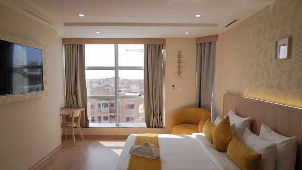A hotel room with a large bed, a chair, a desk, and a TV.