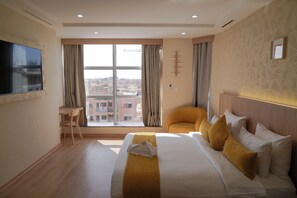 A hotel room with a large bed, a chair, a desk, and a TV. - Sahariano Hotel City Center (Laayoune)