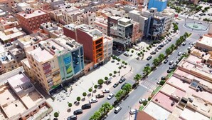 An aerial view of a cityscape with a prominent building featuring a large advertisement on its facade.