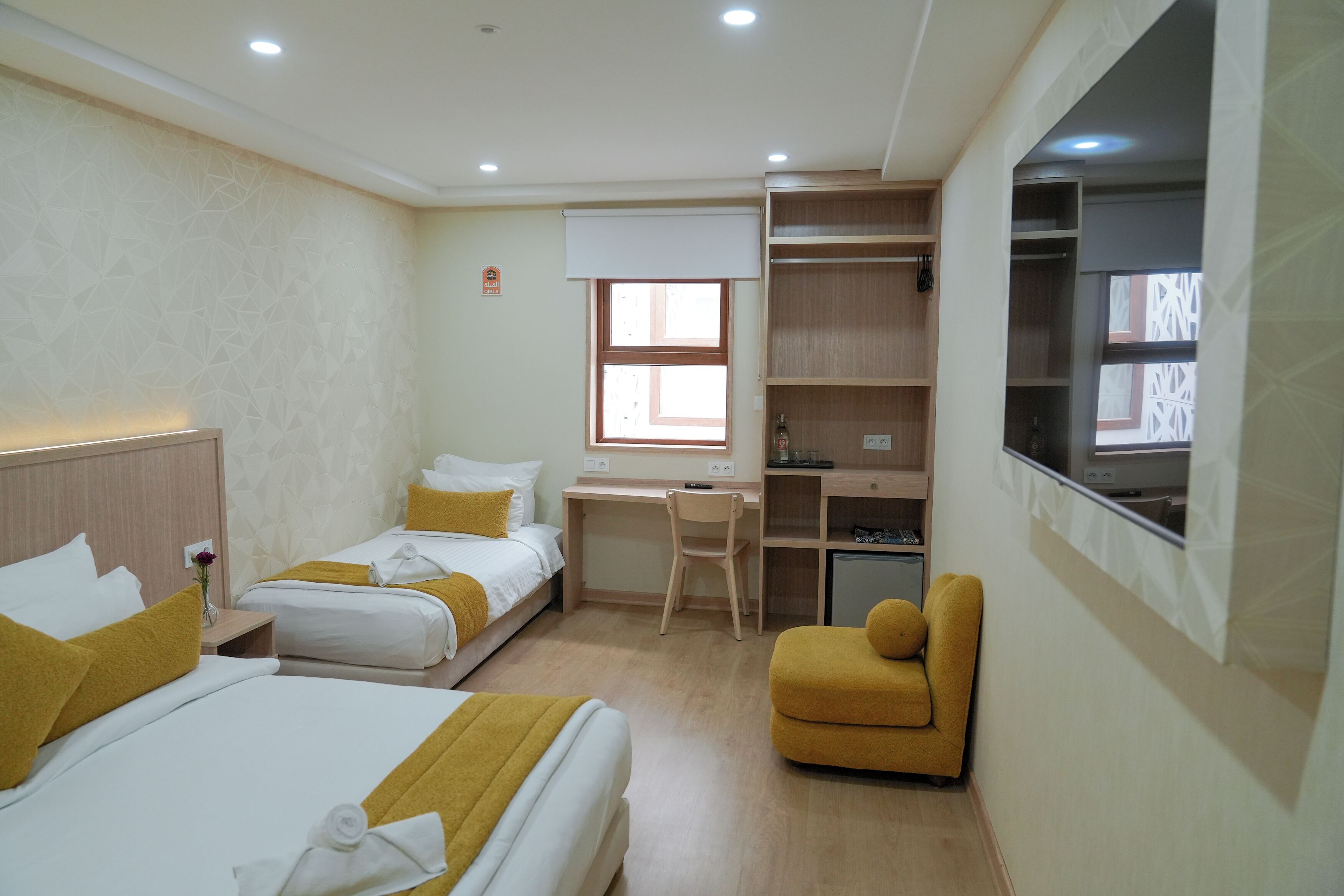 Habitación de hotel con dos camas, un escritorio, una silla, un armario y una ventana.