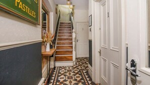 A staircase with a patterned floor, a wall-mounted sign, and a door with a number.