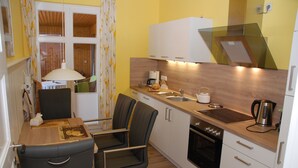 A compact kitchen with a dining area, a coffee maker, a kettle, and a microwave.