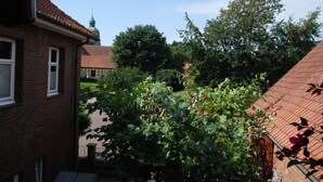 A courtyard with a brick building, a tree, and a distant church spire.