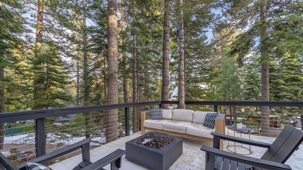 A deck with a sofa and chairs, surrounded by tall trees. - Modern cabin retreat! Cozy, scenic, and serene! (Carnelian Bay)