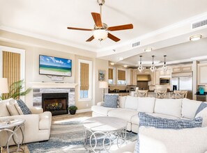 A spacious living room with a fireplace, a large sofa set, a dining area, and a kitchen with modern appliances.