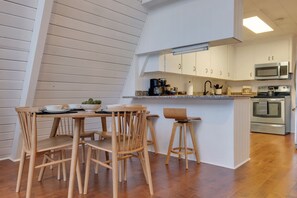 A modern kitchen with white cabinets, a stainless steel oven, and a microwave.