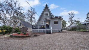 Une maison à deux étages avec un porche à l’avant, une allée en gravier et un petit jardin.