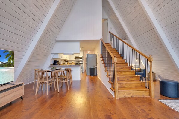 A modern loft with a wooden staircase, a dining area, and a kitchen.